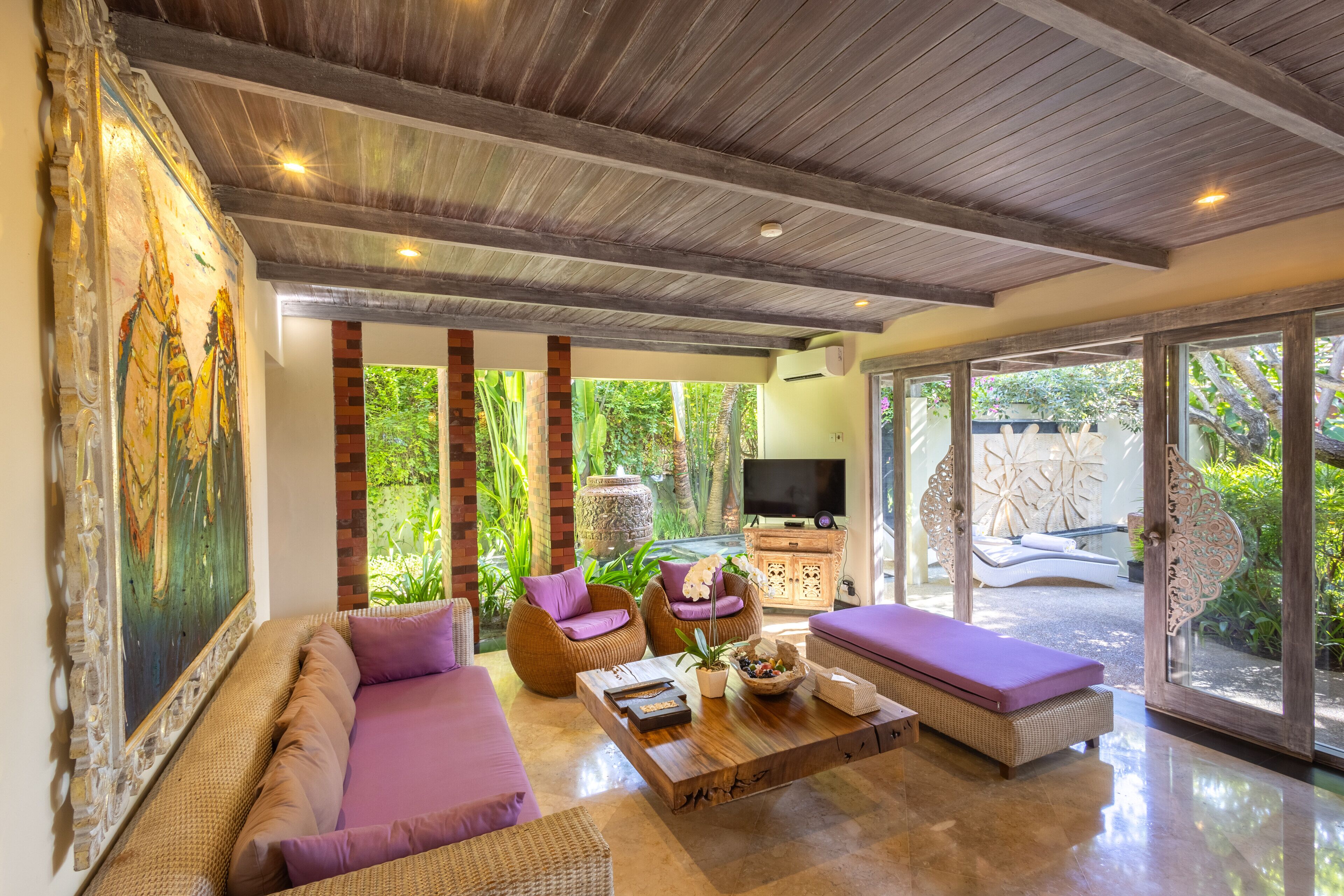 A spacious living area with a large sofa, two armchairs, a coffee table, and a television.