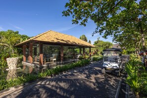 A covered pavilion with a tiled roof, surrounded by lush greenery and a paved pathway. - The Royal Purnama Luxury Villas - Adults Only (Sukawati)