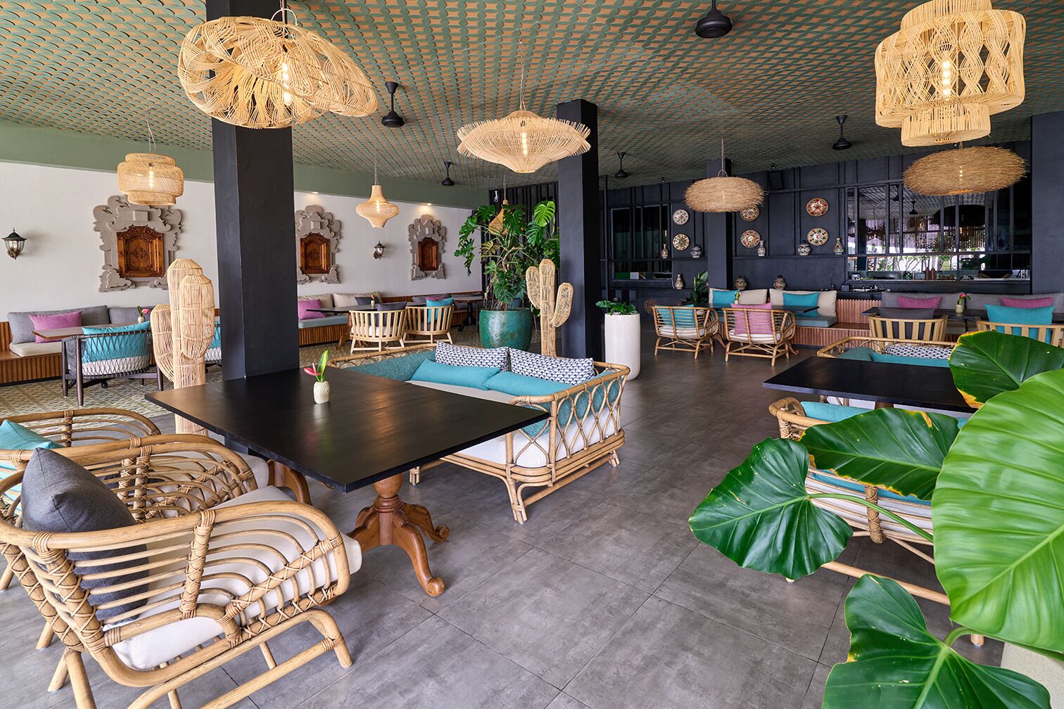 A spacious indoor area with wicker furniture, large windows, and hanging wicker lamps.