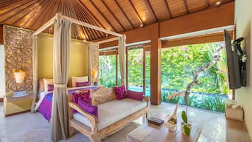 Relax in a serene bedroom with a four-poster canopy bed and a view of lush greenery.