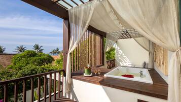 A balcony with a wooden floor, a white bathtub, and a green potted plant.