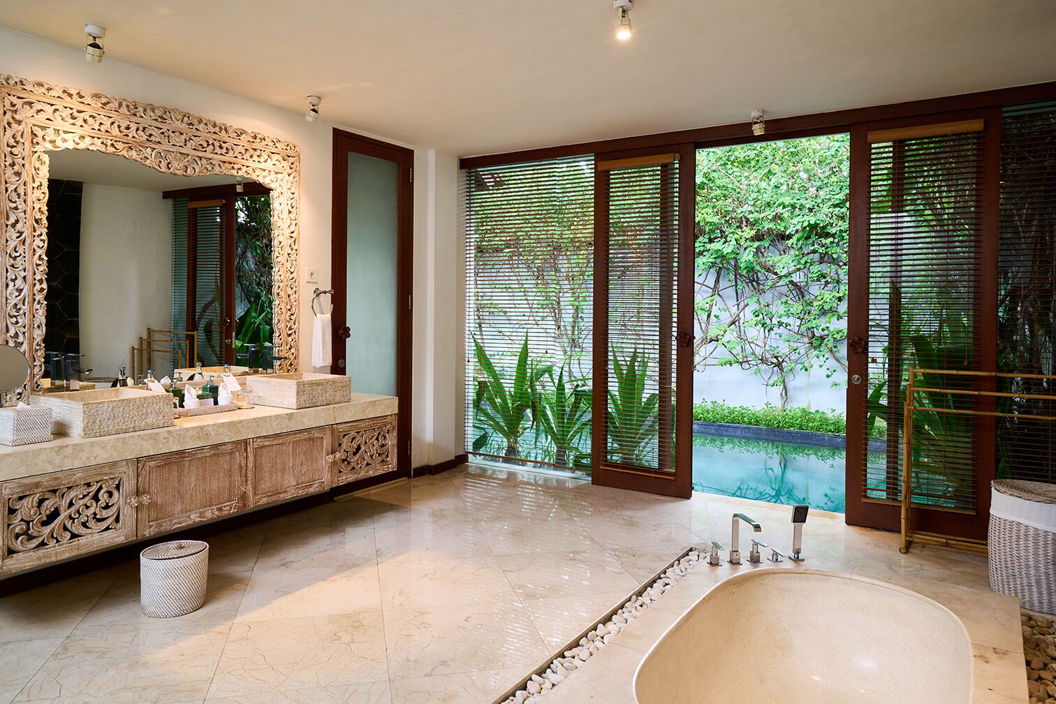 A bathroom with a large bathtub, a double sink vanity, and a large mirror.