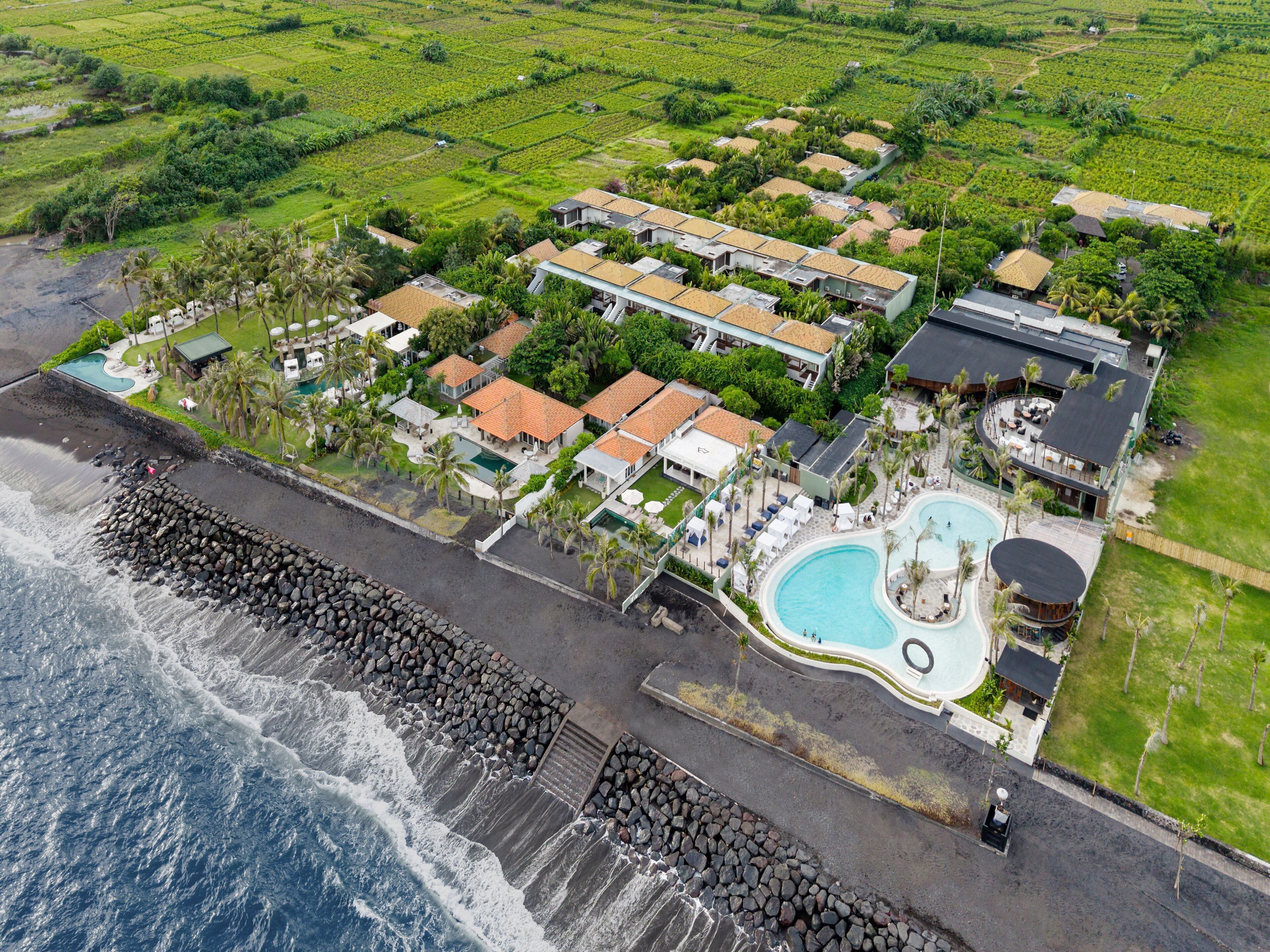 A coastal resort with a swimming pool, beachfront villas, and a rocky breakwater.
