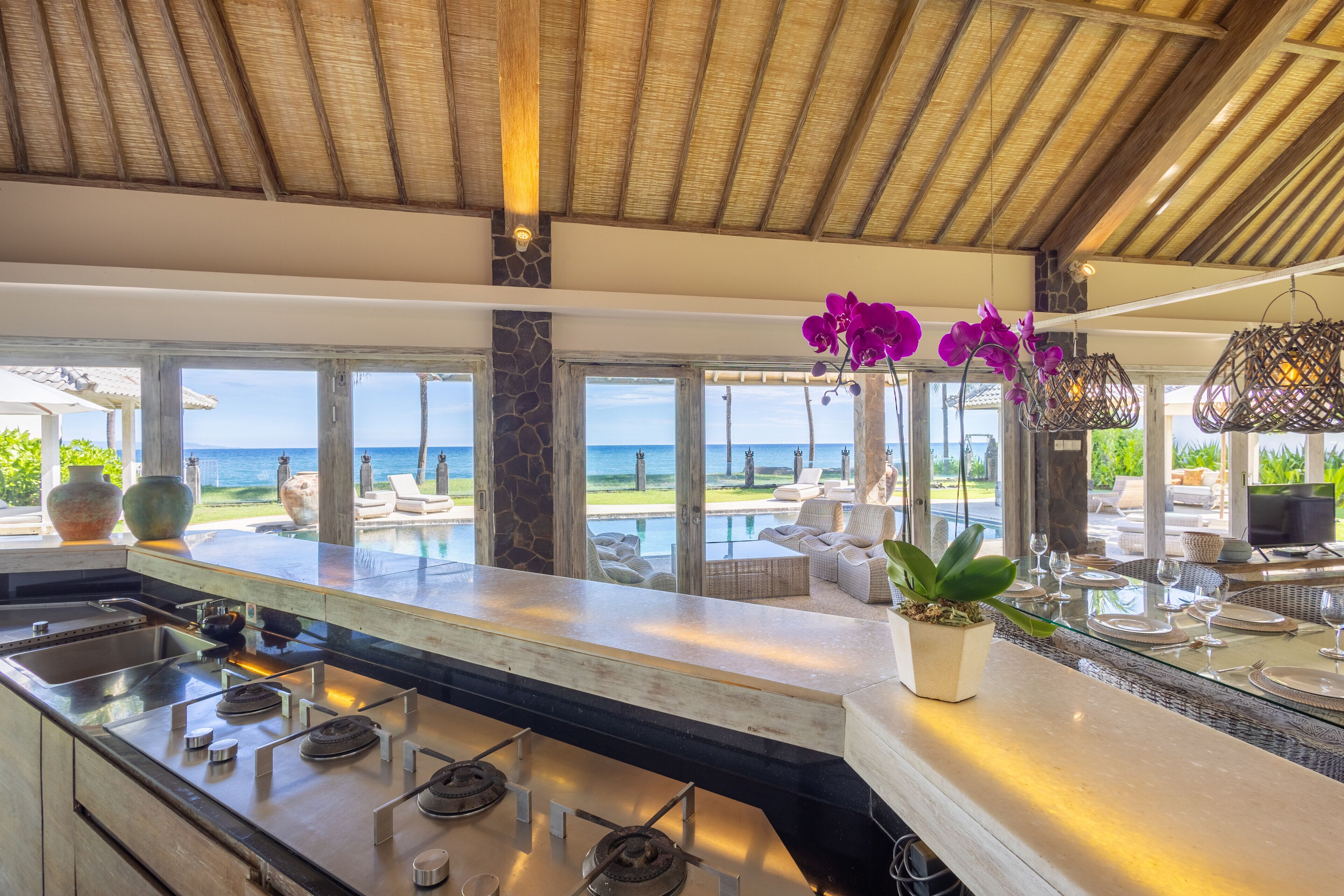 Una cocina moderna con una isla grande, una pared decorativa de piedra y vistas al océano.
