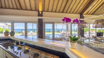 Una cocina moderna con una isla grande, una pared decorativa de piedra y vistas al océano.