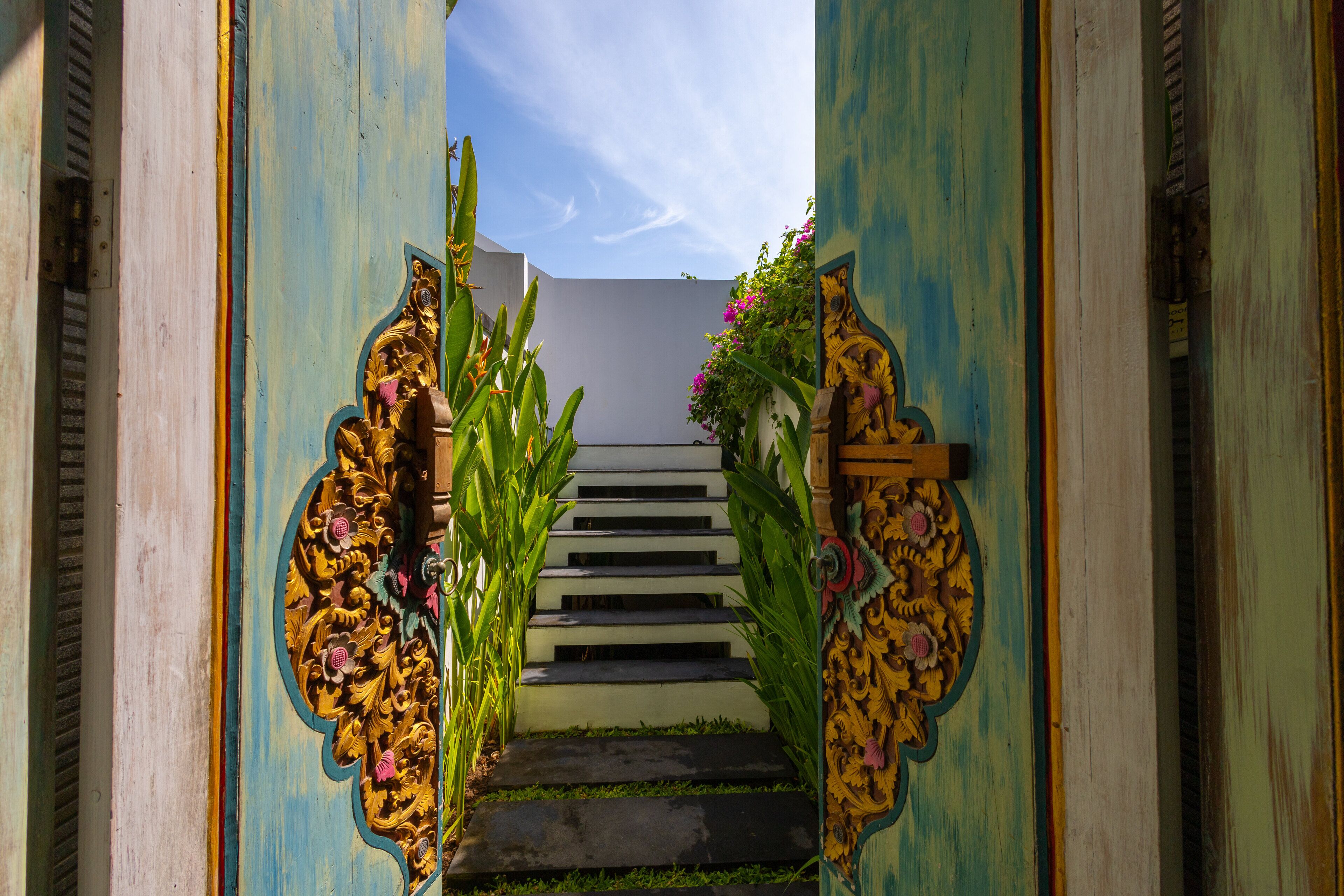 A staircase with ornate golden decorations and floral arrangements leading to a white door.