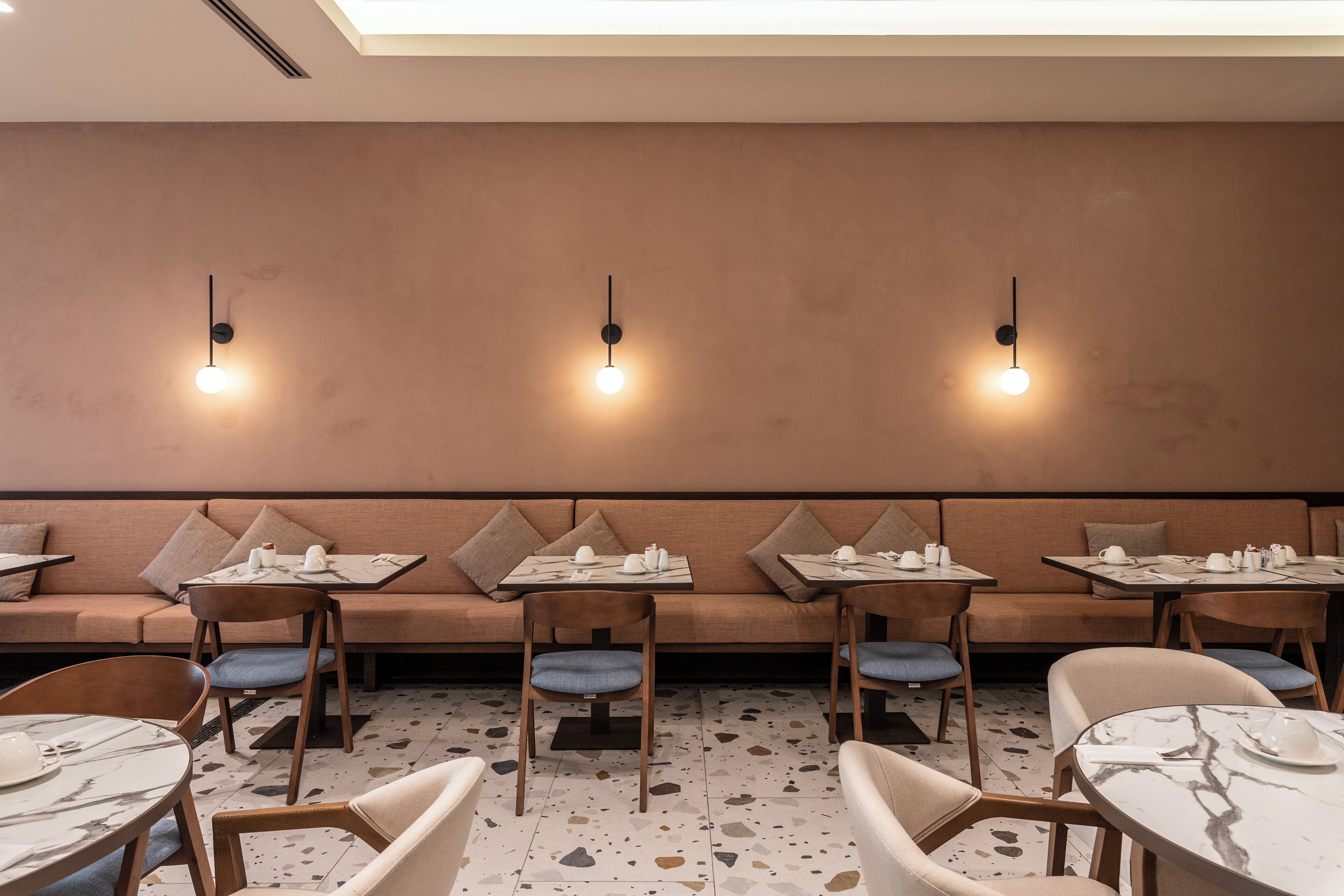 Un restaurant au décor moderne, avec de longues banquettes, des tables individuelles et un sol à motifs.