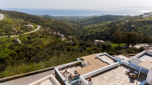 A rooftop terrace with a stone floor, outdoor furniture, and potted plants. - Amalgam Homes Tinos (Tinos)