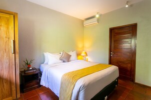 A bedroom with a bed, nightstand, lamp, and an air conditioning unit.