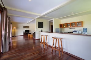 A spacious kitchen with wooden bar stools, a microwave, and a water dispenser.