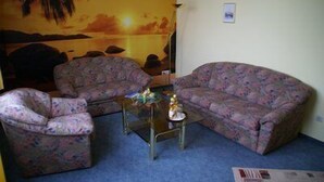 Un salon avec deux canapés à motifs, une petite table basse et une fresque murale représentant un coucher de soleil.
