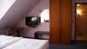 Une chambre à coucher avec un lit, une télévision, un bureau et une armoire.