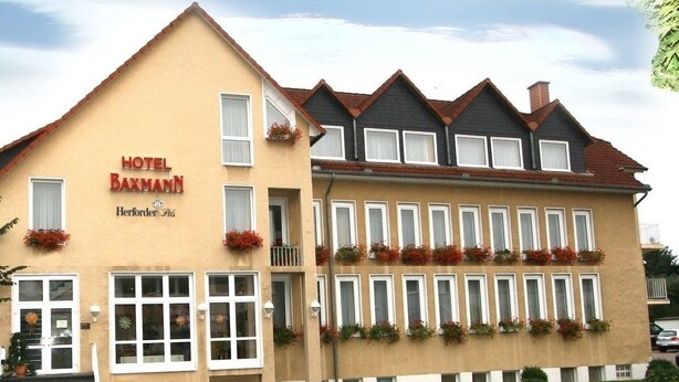 Un hôtel à la façade beige, doté de nombreuses fenêtres et de jardinières au deuxième étage.
