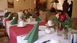 Un espace repas avec des tables dressées pour deux personnes, agrémenté de nappes rouges, d’assiettes blanches et de serviettes vertes.
