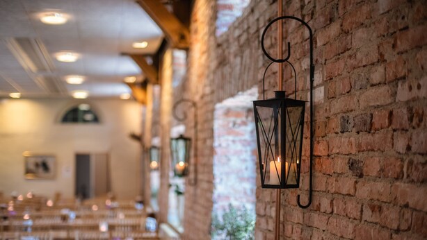 Un restaurant aux murs de briques, aux lanternes suspendues et aux tables en bois.