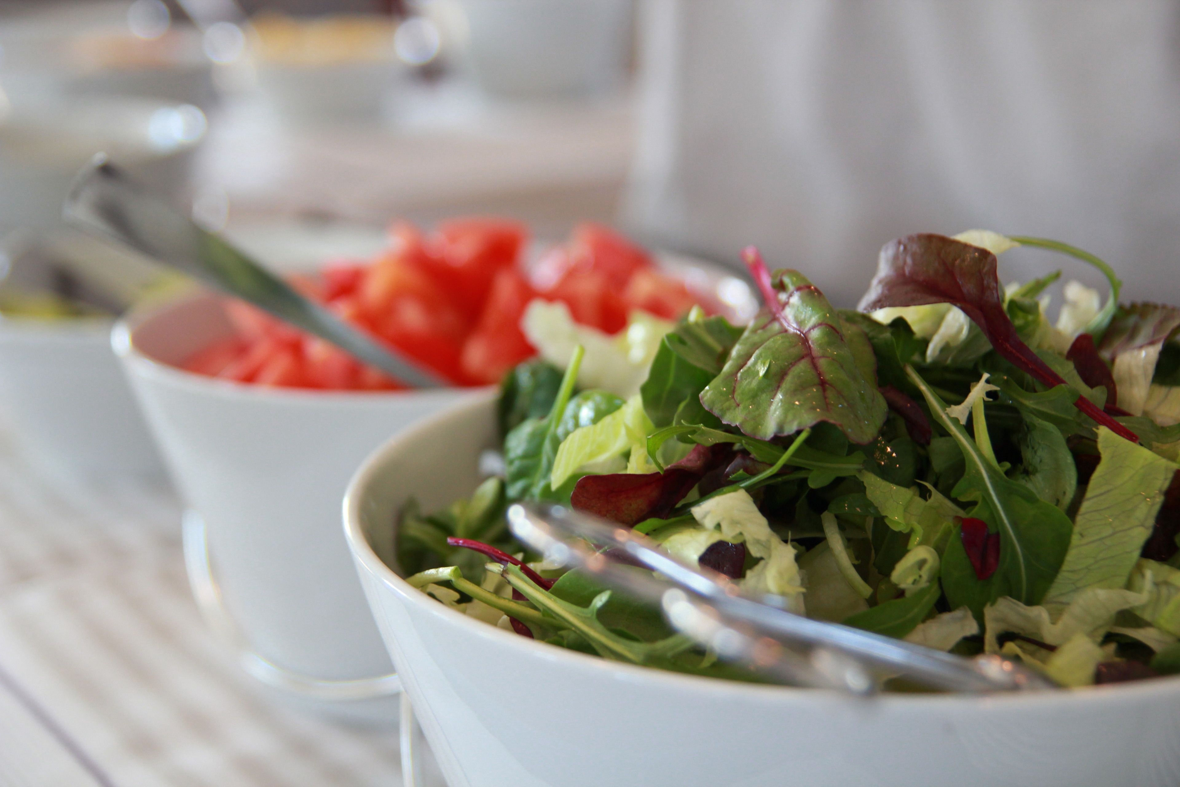 A bowl of salad with various greens and a spoon.