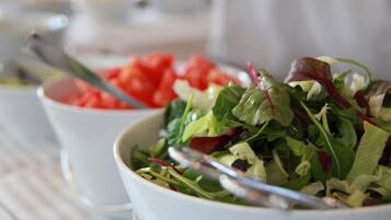 A bowl of salad with various greens and a spoon.
