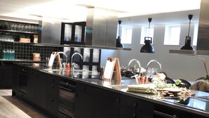 Une cuisine moderne avec des meubles de couleur noire, des appareils en acier inoxydable et un long plan de travail.