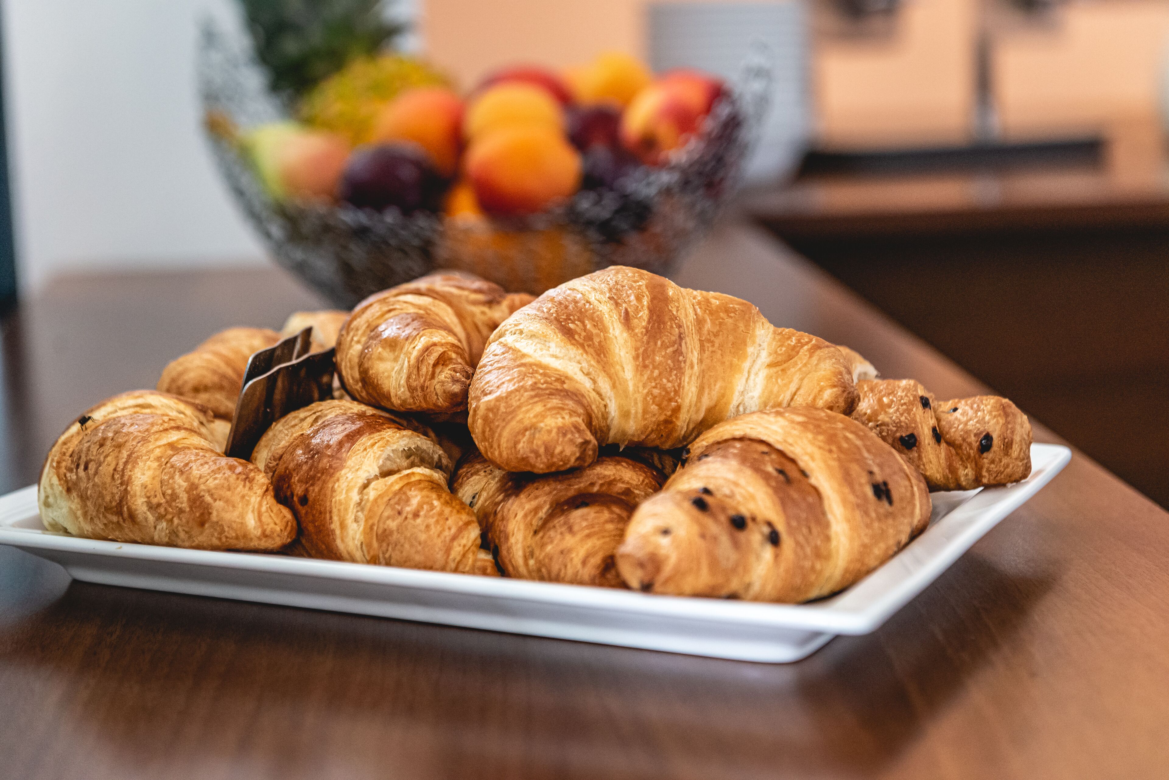 A plate of croissants on a white rectangular plate.