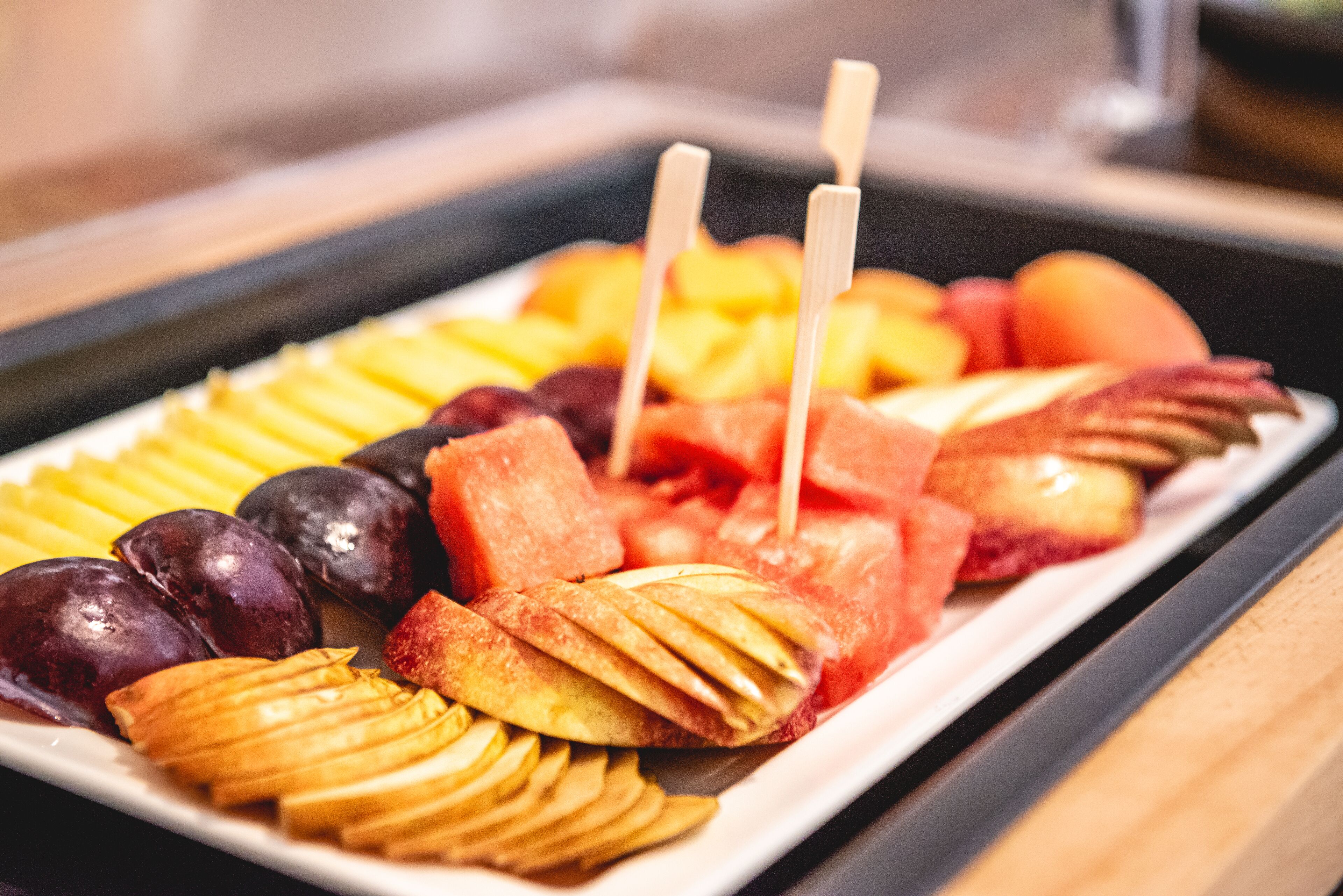 Eine Obstplatte mit verschiedenen Früchten und Holzspießen.