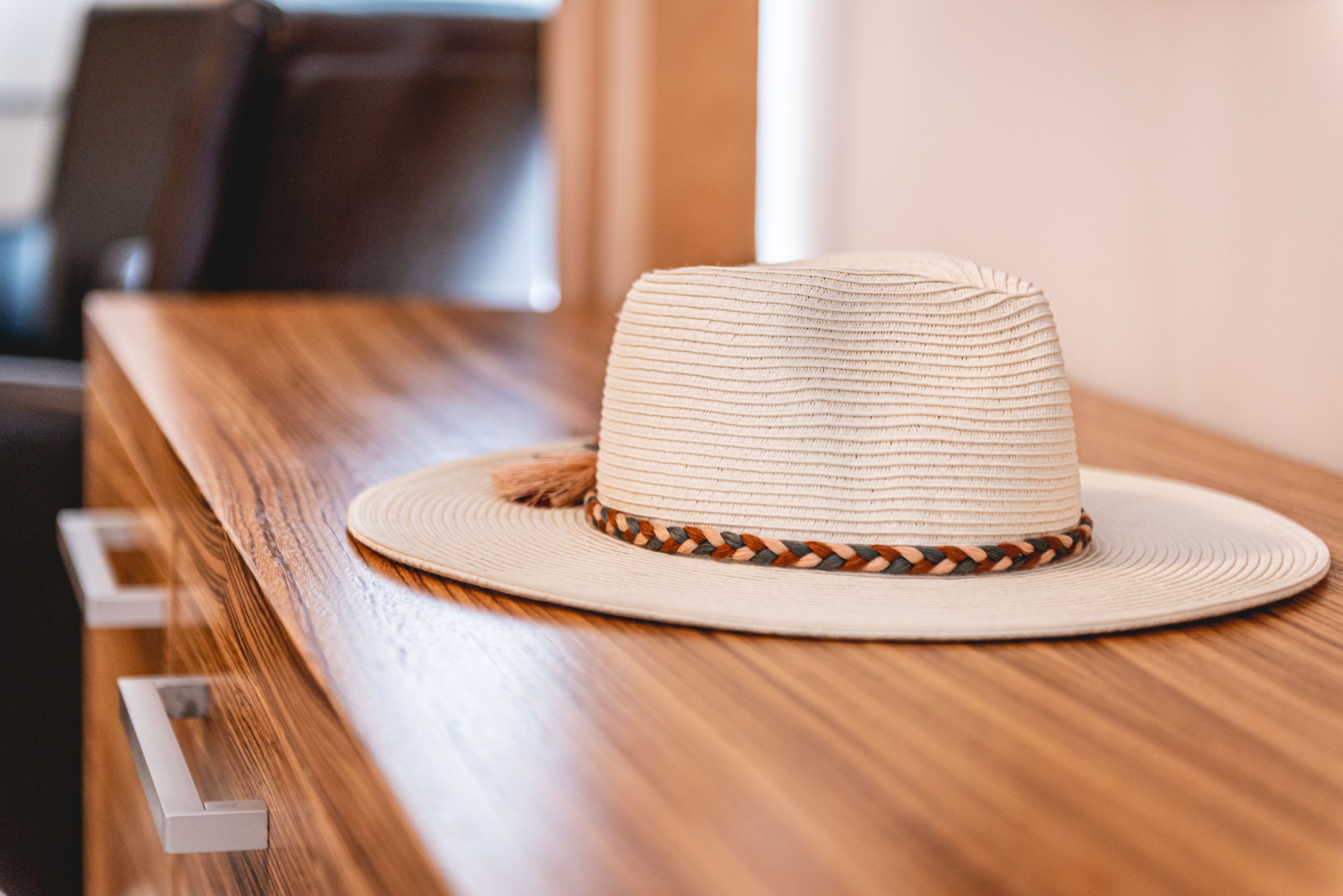 A straw hat with a braided band on a wooden table.