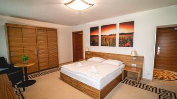 A bedroom with a large bed, wooden wardrobe, a small table with a plant, and two wall-mounted lamps.