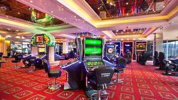 A casino with multiple slot machines, bar stools, and a red carpeted floor.