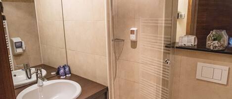 A modern bathroom with a glass-enclosed shower, a sink, and a toilet.
