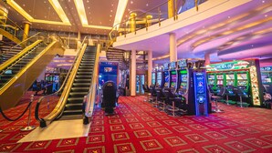 A casino interior with a red carpet, slot machines, and an escalator. - Casino & Hotel ADMIRAL Kozina (Hrpelje-Kozina)