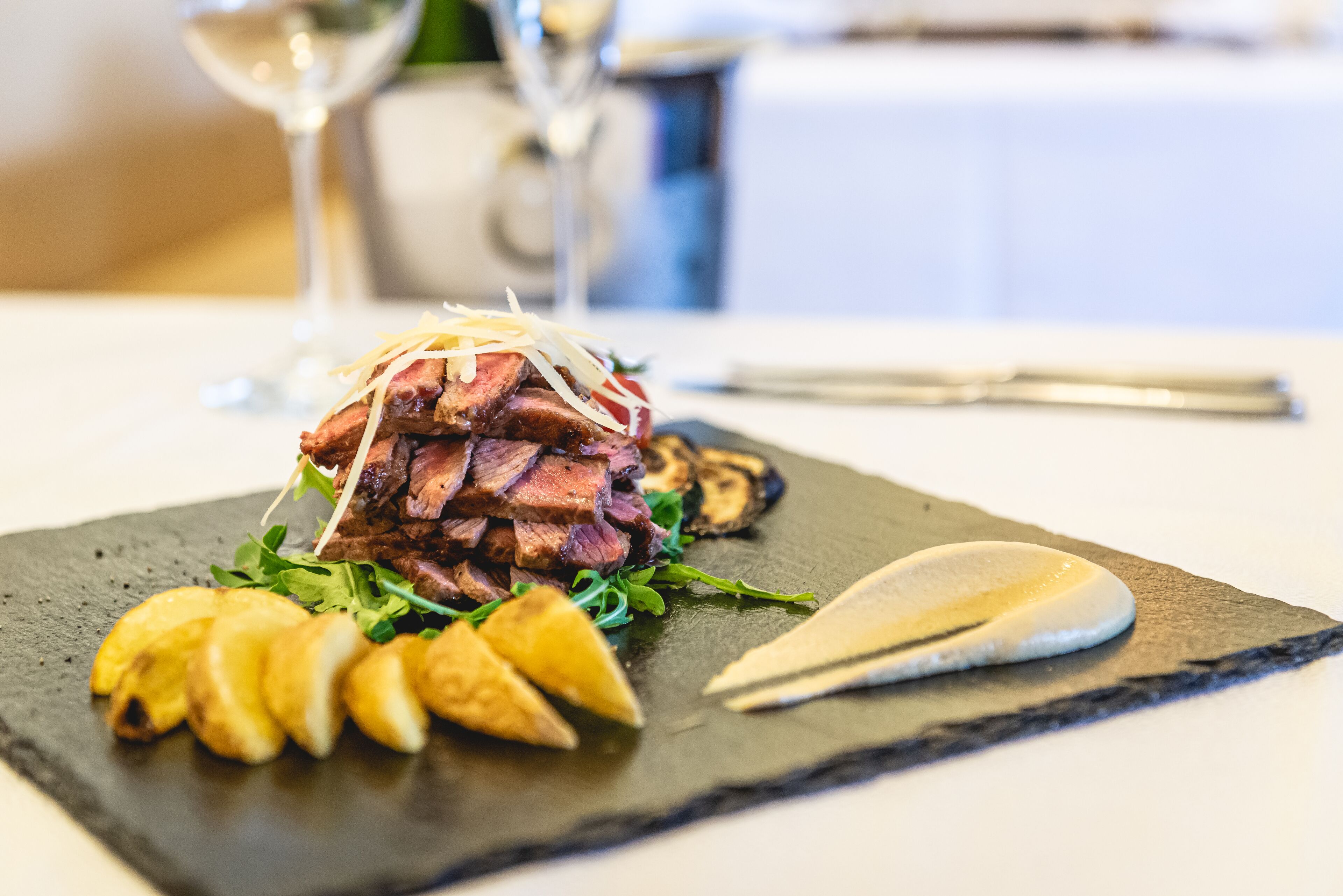 Um prato de bife com batatas assadas e legumes verdes.