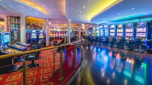 A casino with multiple slot machines, a red carpeted area, and a curved ceiling with recessed lighting. - Casino & Hotel ADMIRAL Kozina (Hrpelje-Kozina)