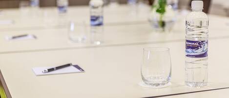 A conference table with water bottles, glasses, and a pen.