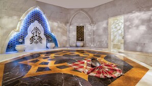 Een luxueuze lobby met een patroon vloer, een decoratieve boog en een grote witte pot.