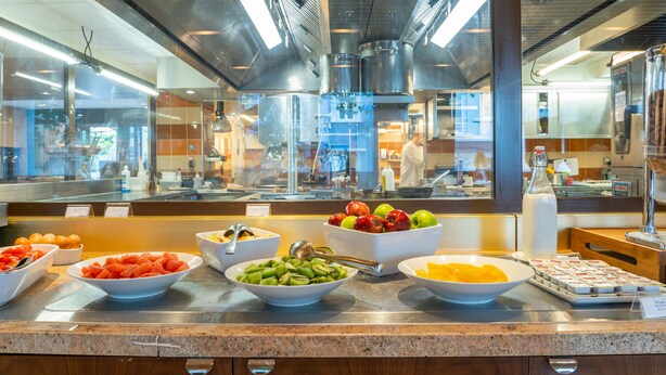 Balcão de buffet com diversos alimentos e um dispensador de bebidas.
