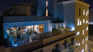 Um edifício moderno com fachada de vidro, área de estar ao ar livre e interior visível com lareira.