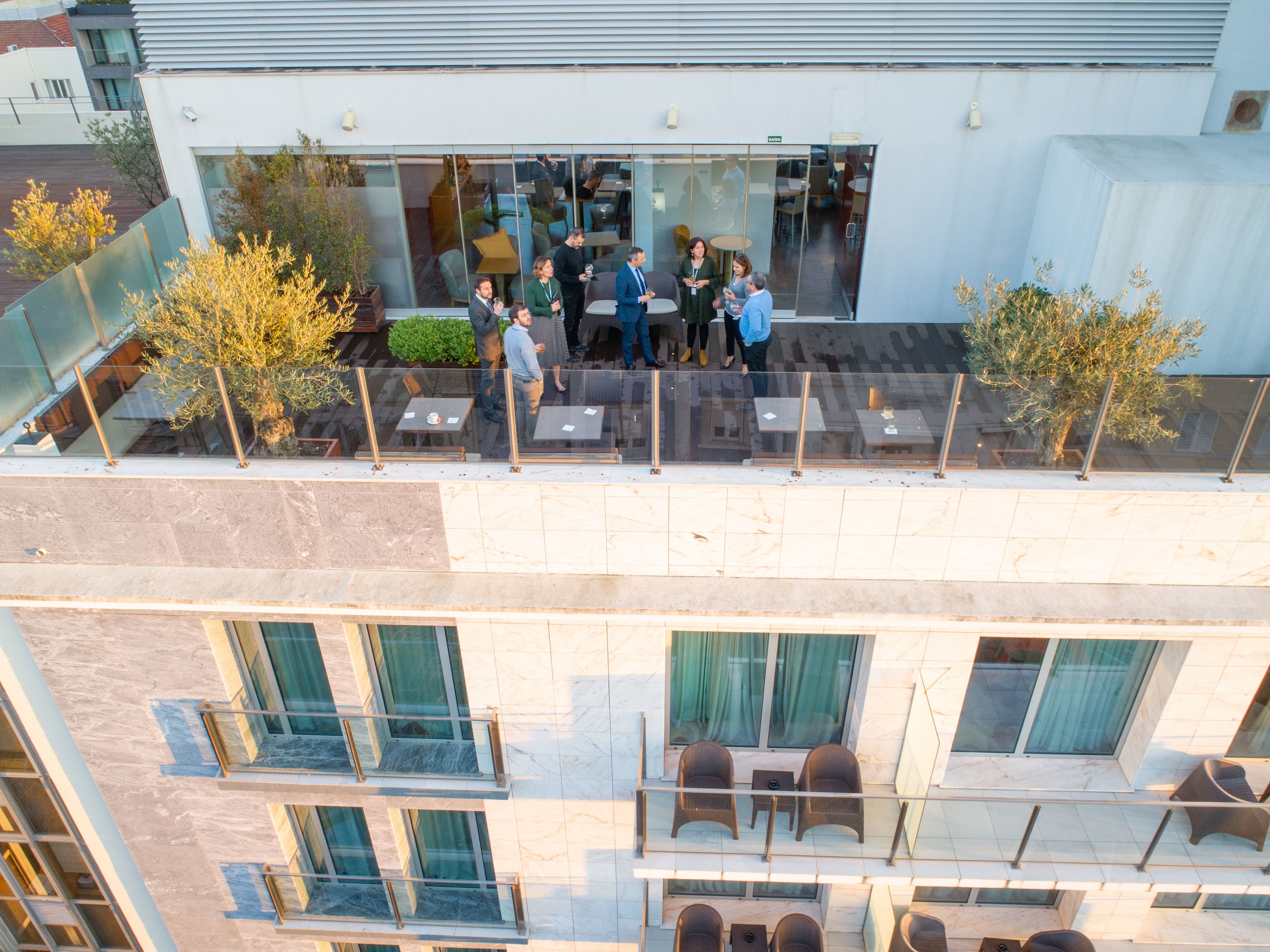 A modern building with a glass exterior, outdoor seating area, and multiple balconies.