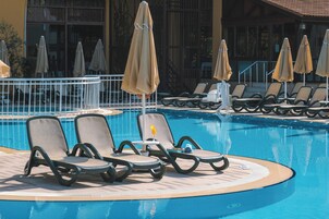 Uma área à beira da piscina com espreguiçadeiras e guarda-sóis.