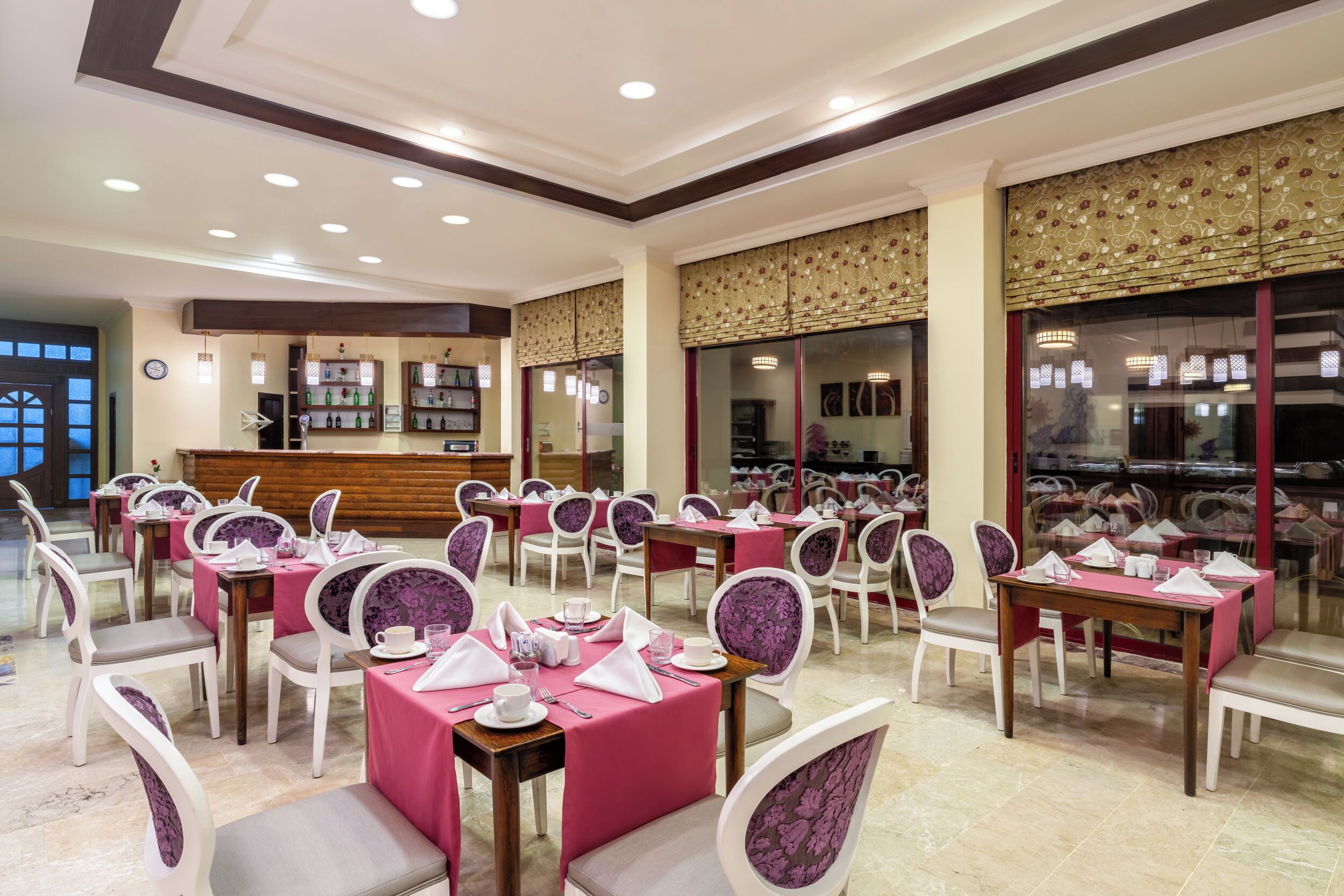 A restaurant with tables set for dining, a reception area, and decorative elements.