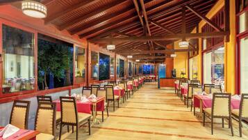Un restaurante con mesas largas, sillas y un techo alto con vigas de madera.