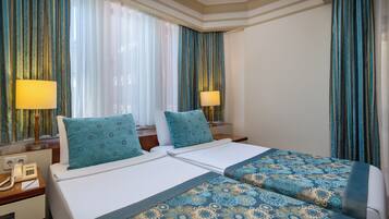 Habitación de hotel con dos camas, un escritorio y teléfono, y cortinas.