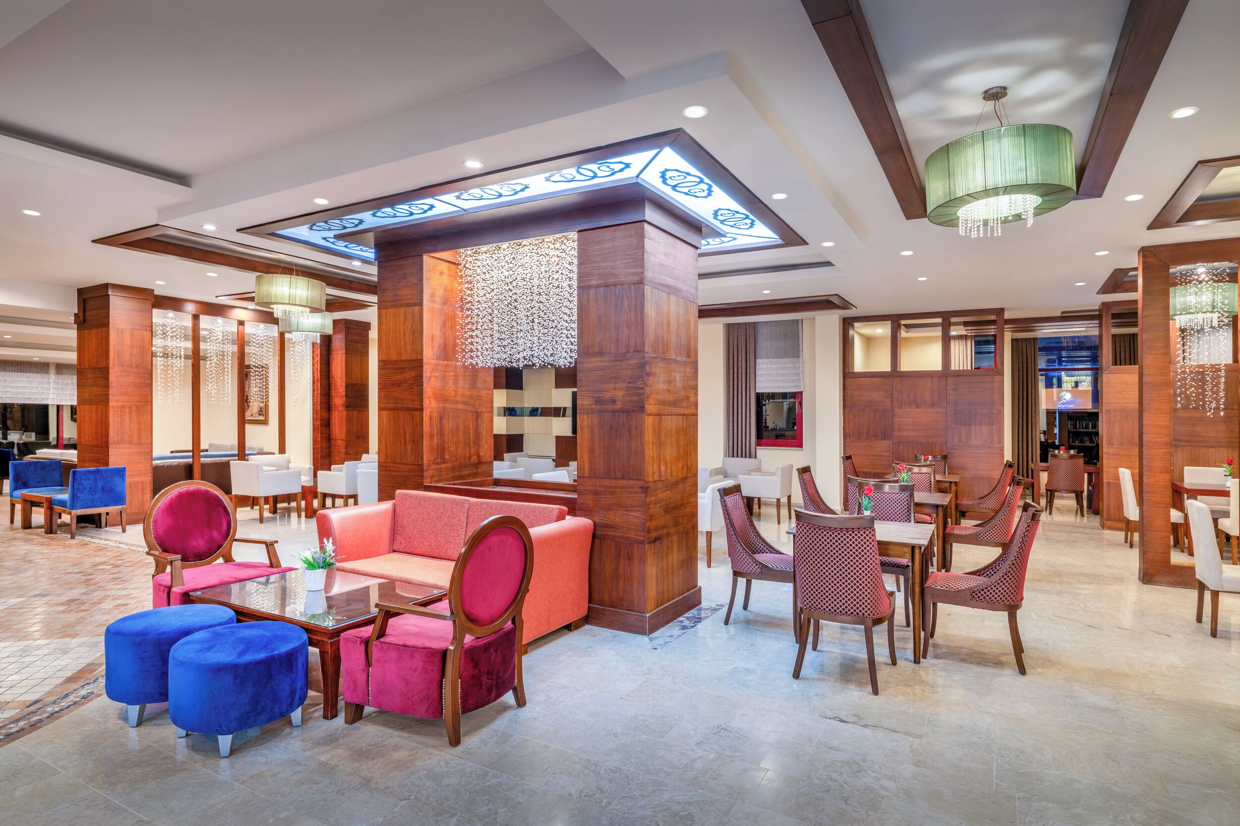 Een hotel lobby met een zithoek, een receptiebalie en een kroonluchter.