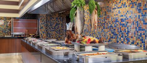 A buffet with various food stations and a decorative tree with hanging greenery.