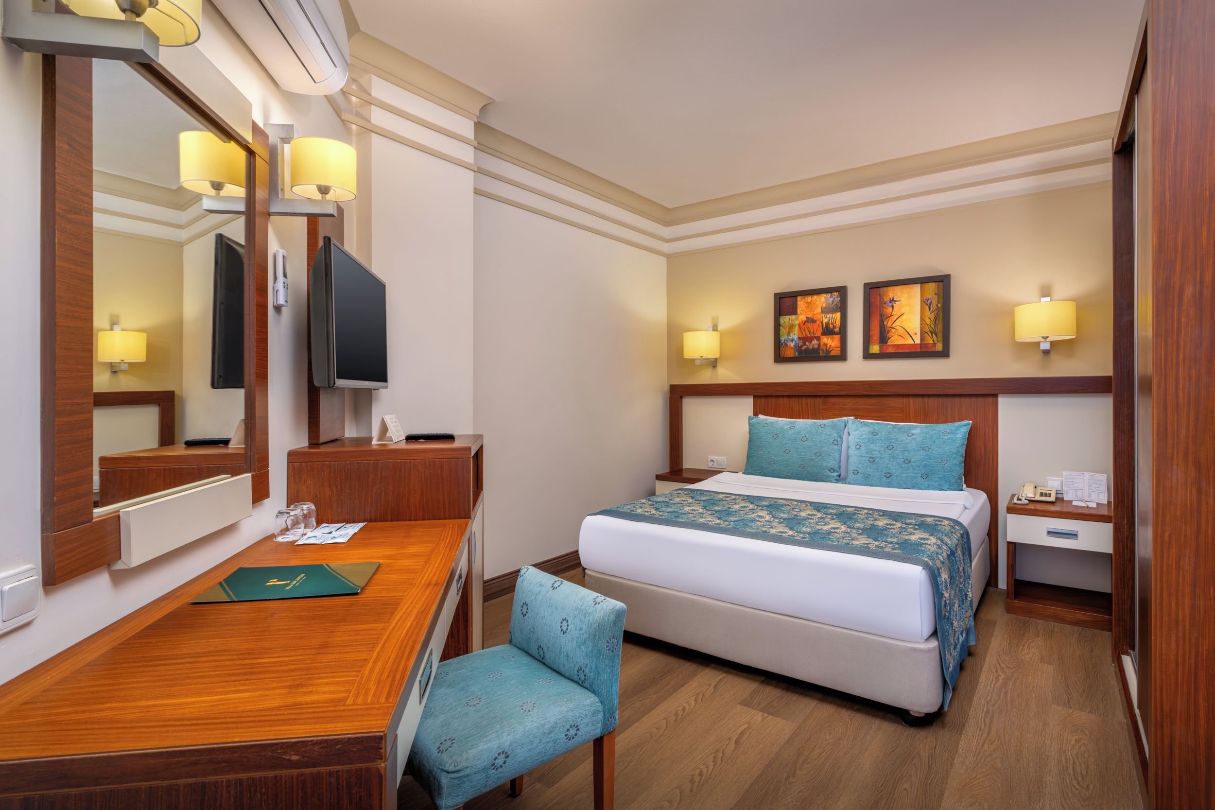 A hotel room with a bed, a desk, a chair, a television, and a nightstand.