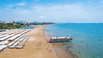 Een privéstrand, ligstoelen aan het strand, parasols, een strandbar