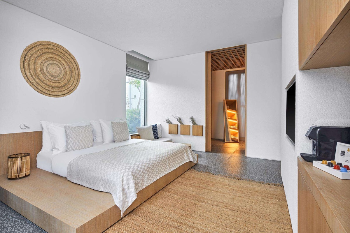 Ein modernes Hotelzimmer mit einem großen Bett, einer hölzernen Bank, einem Fernseher und einem Kamin.