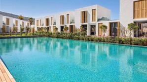A modern hotel with a pool, white exterior walls, and wooden shutters. - Voyage Torba (Bodrum)