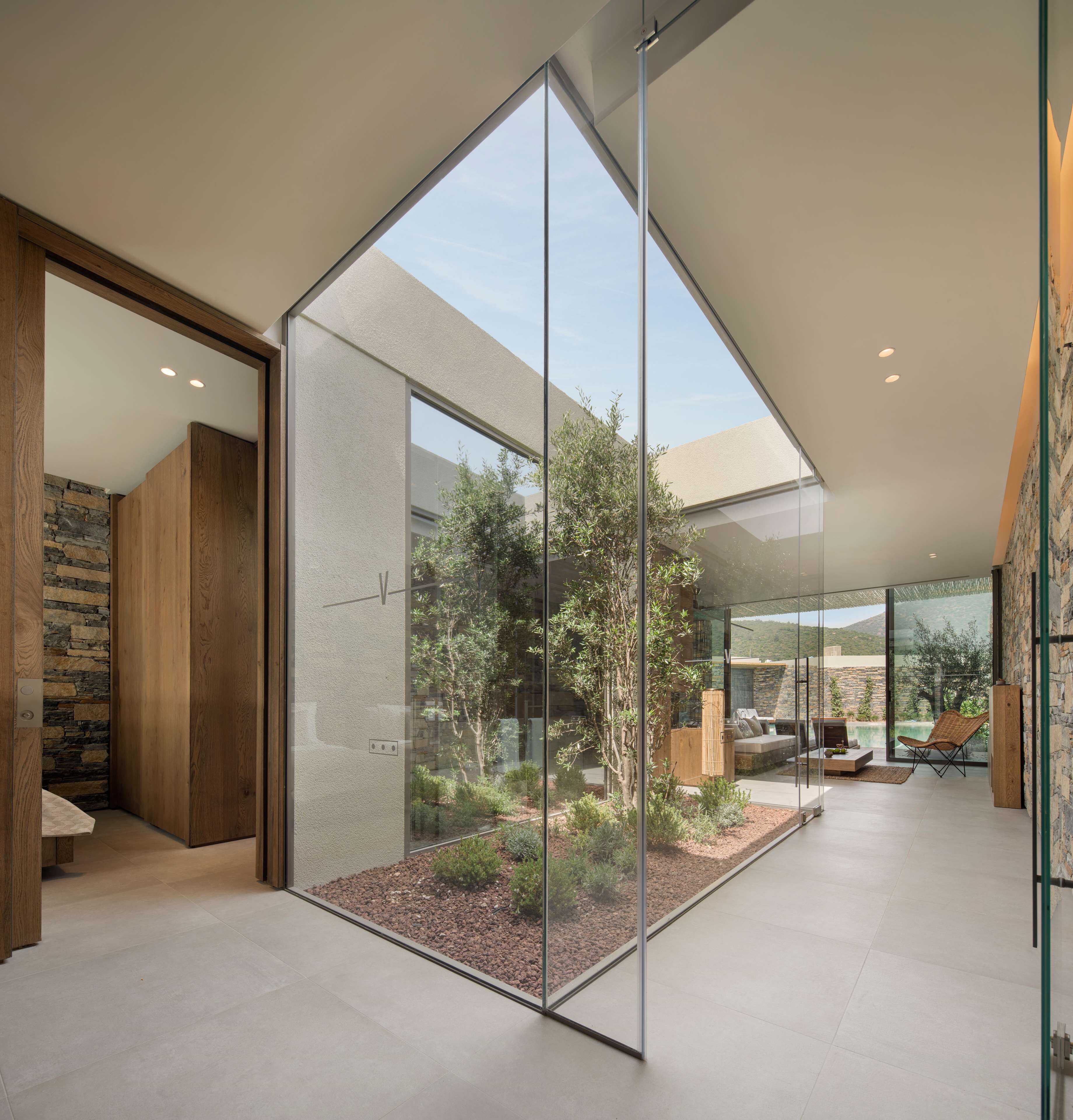A modern interior with a glass partition, stone wall, and a view of an outdoor garden.