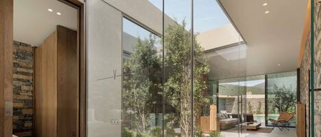 A modern interior with a glass partition, stone wall, and a view of an outdoor garden.