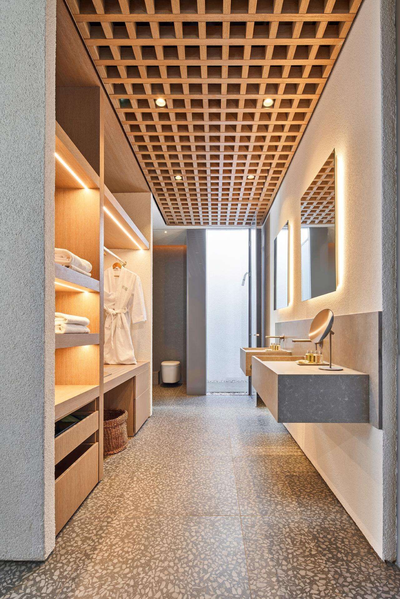 Un baño moderno con techo de listones de madera, cabina de ducha y tocador con espejo.