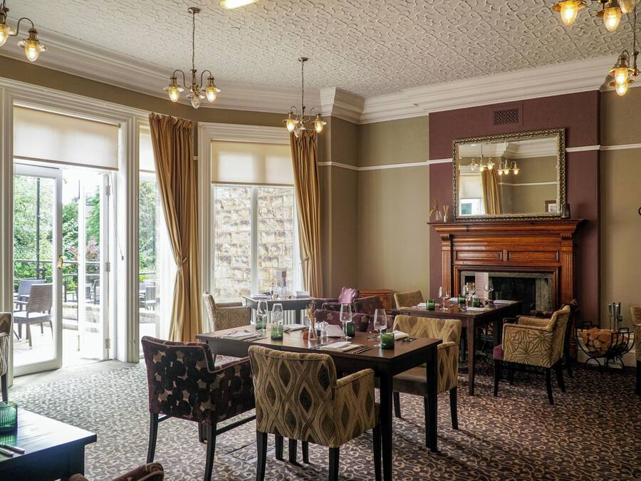 A dining area with a fireplace, patterned chairs, and a table set for a meal.